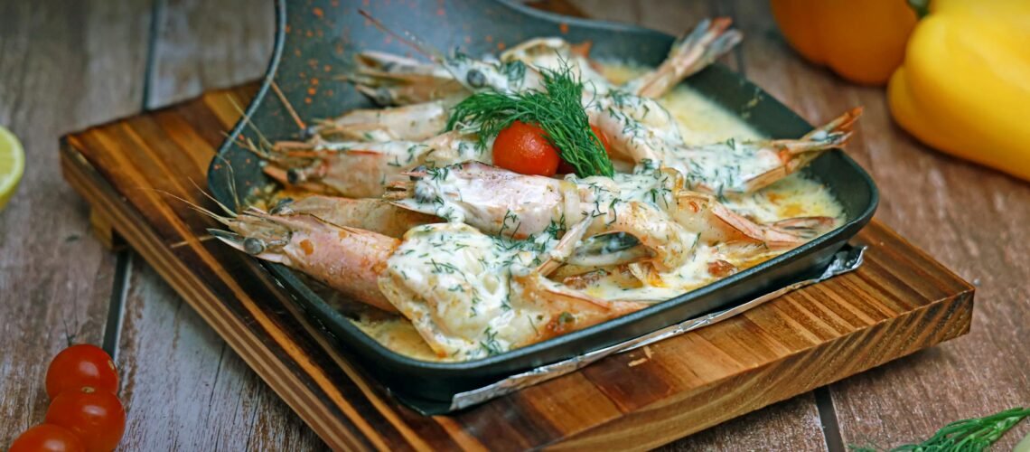 a pan with shrimp and vegetables on a wooden cutting board
