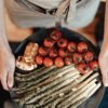 person holding black plate with cherry tomatoes and asparagus